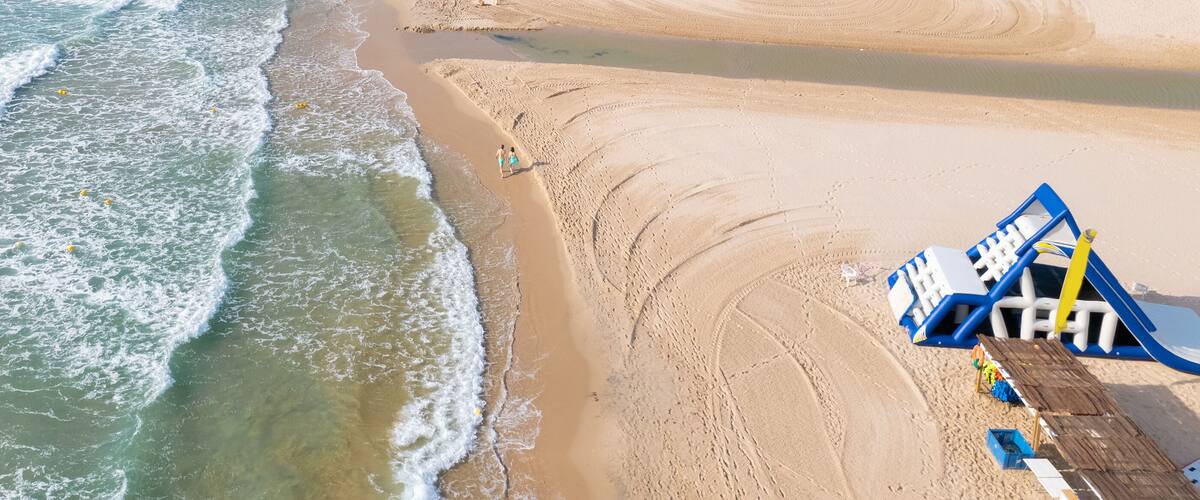 A sandy beach with gentle waves and a blue lifeguard stand.