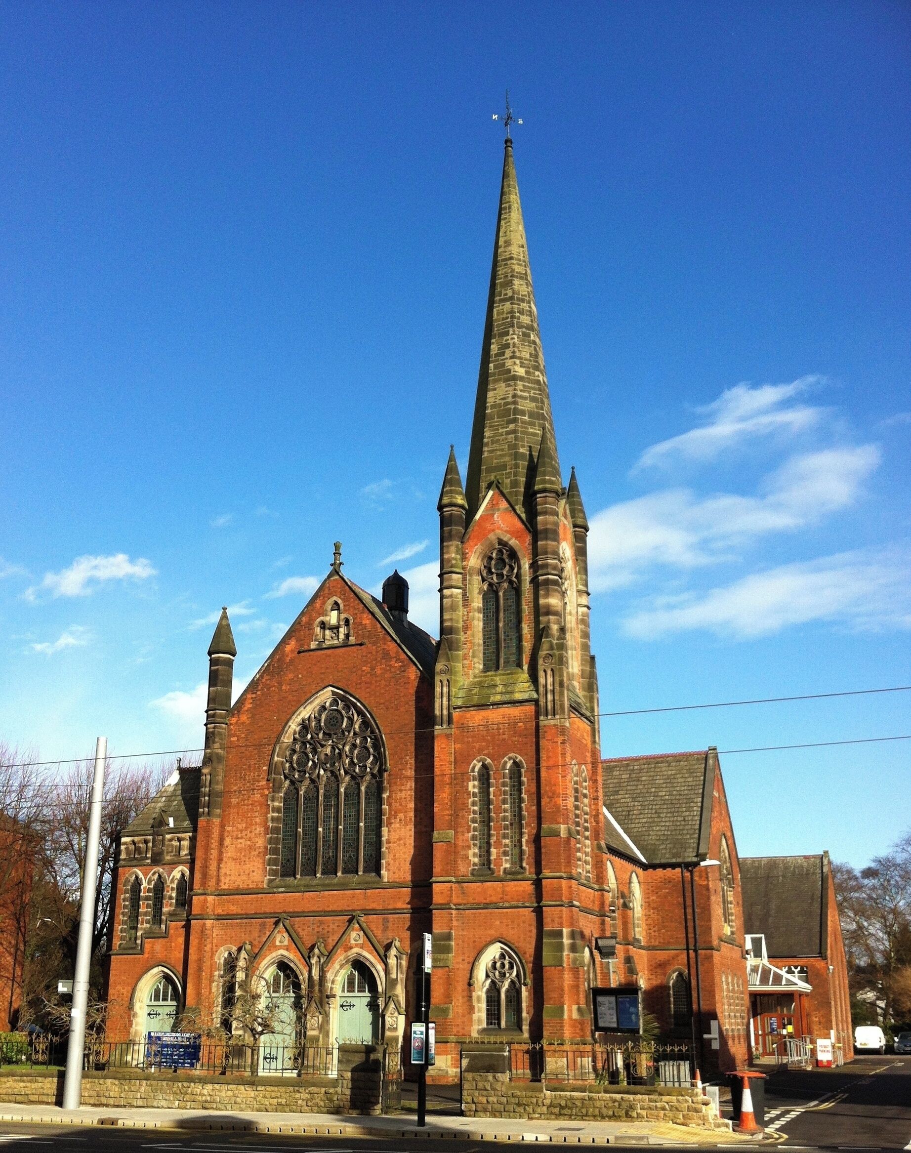 A large brick church with a tall spire and arched windows.