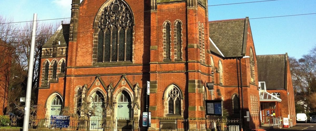 A large brick church with a tall spire and arched windows.