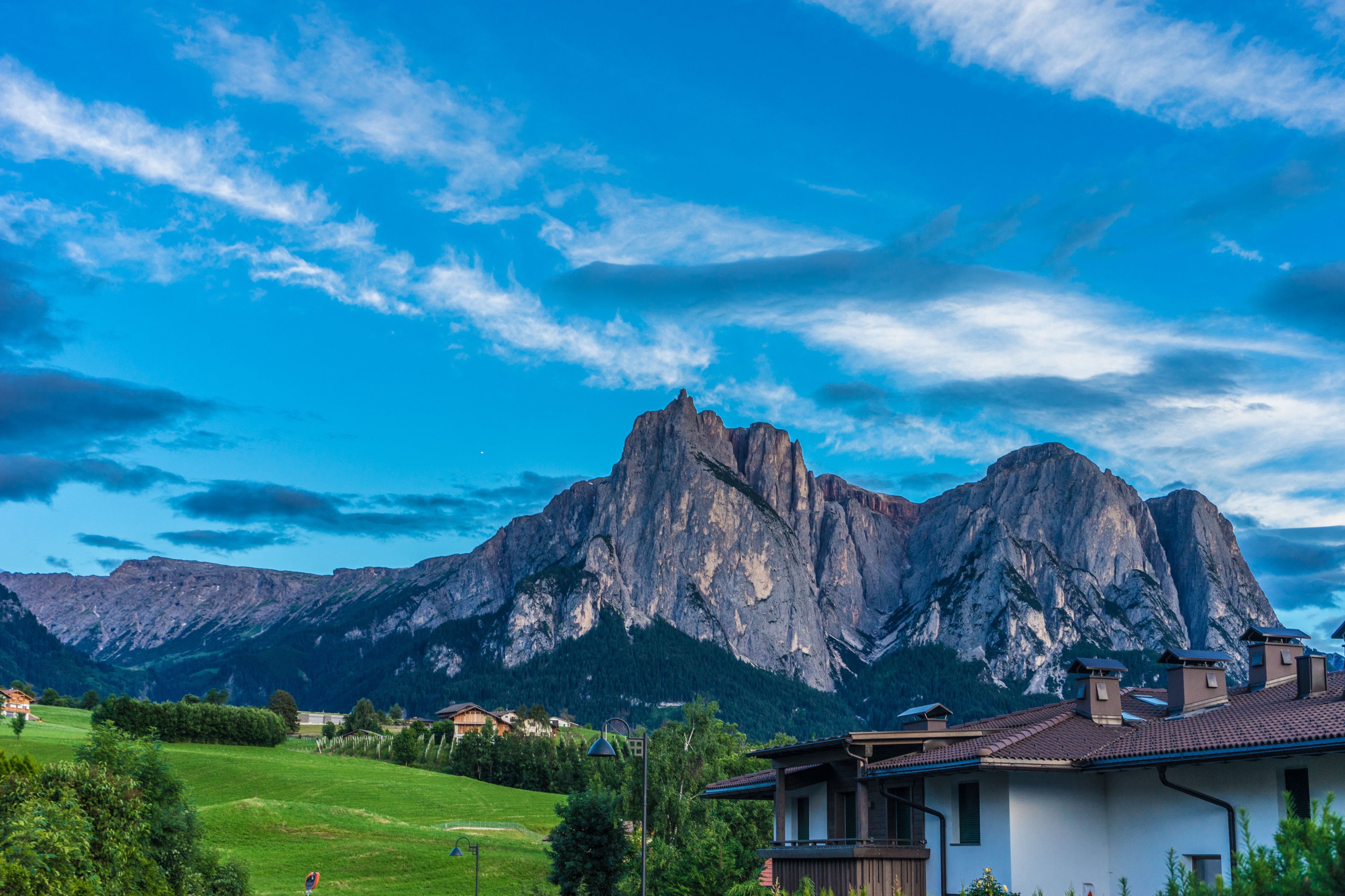 Alpe di Siusi, Seiser Alm with Sassolungo Langkofel Dolomite, a house with a mountain in the background