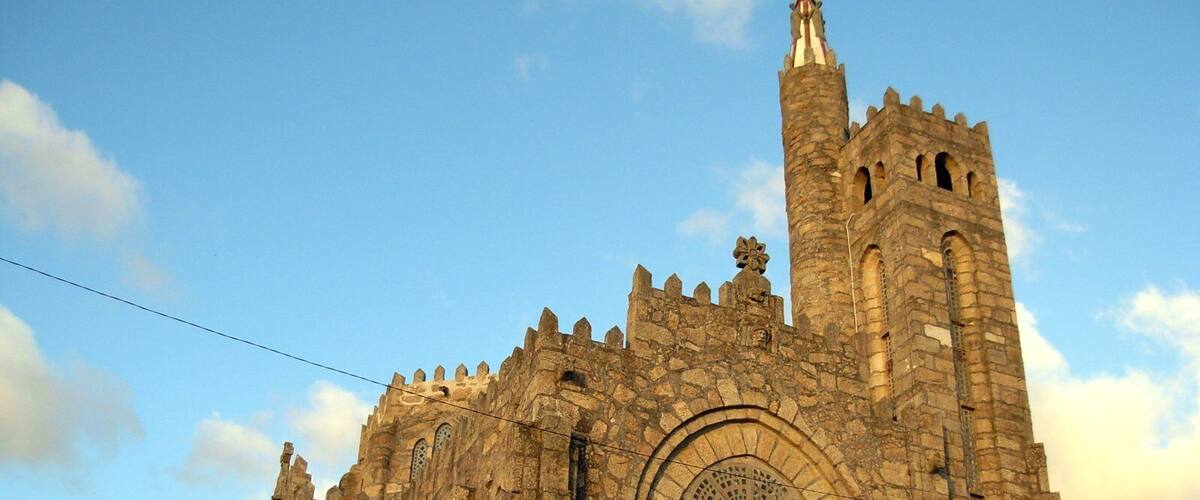 A historic stone cathedral with a tall bell tower and arched windows.