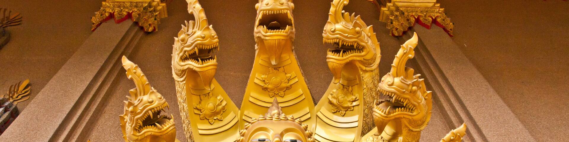 A golden reclining Buddha statue surrounded by ornate golden dragon heads.