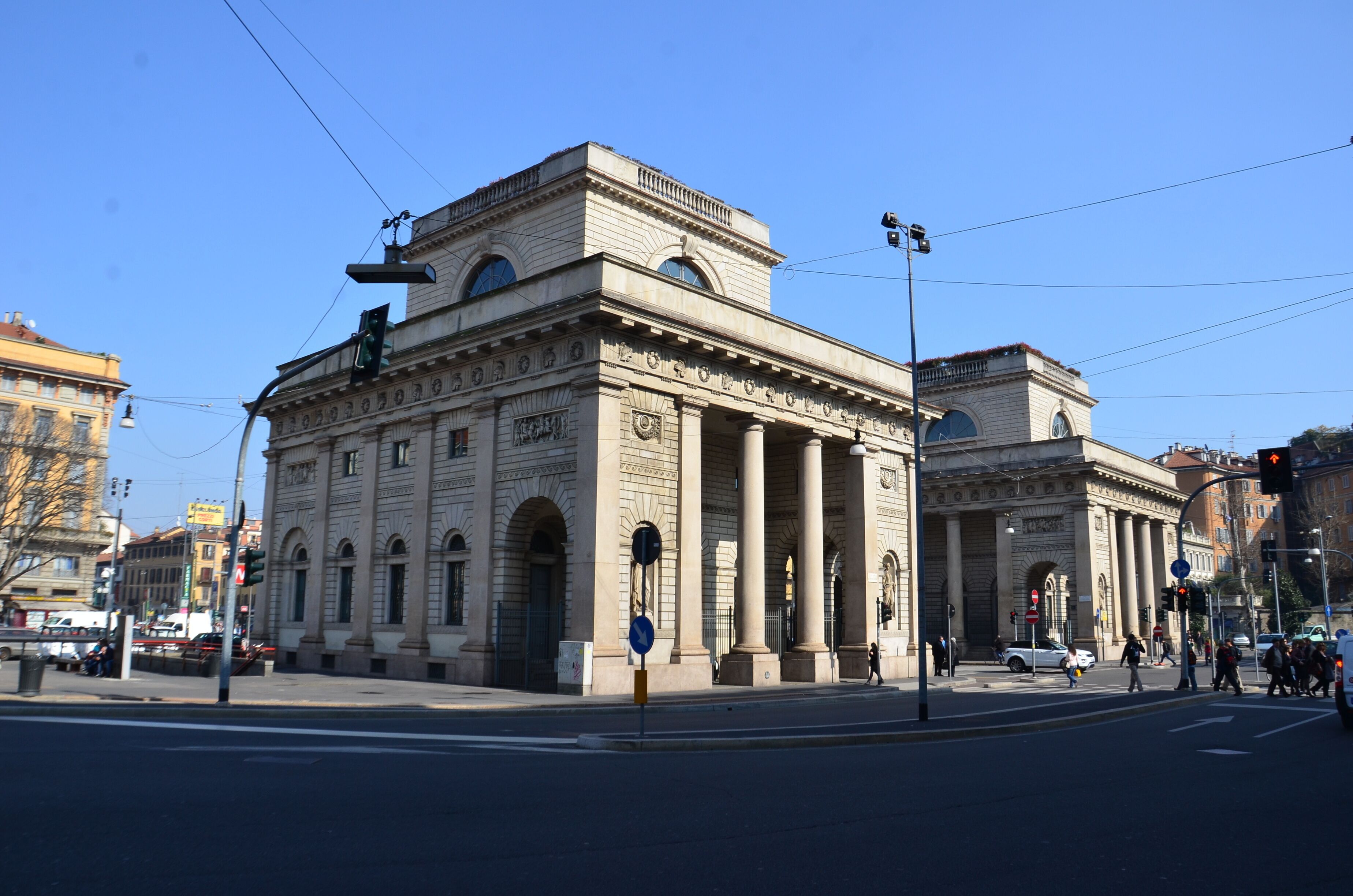 A historic building with classical architecture, including columns and arched windows, located at a city intersection.