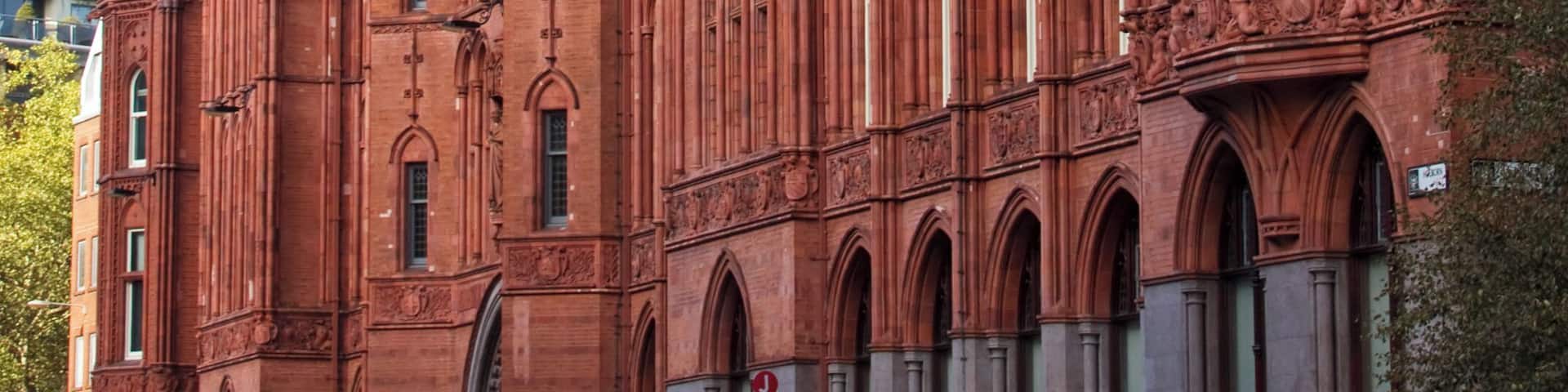 A large red brick building with multiple spires and arched windows.