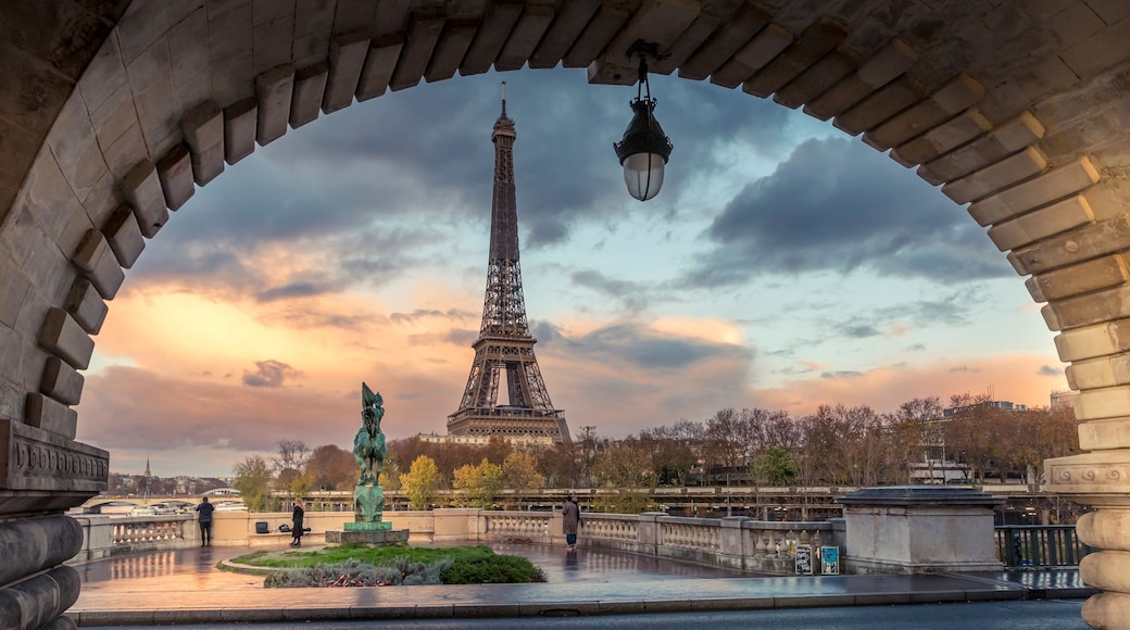 The Eiffel Tower viewed through an archway with a statue in the foreground.