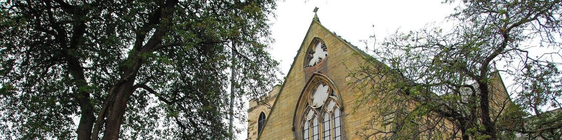 A historic building with a stone facade, large arched windows, and a pointed roof.