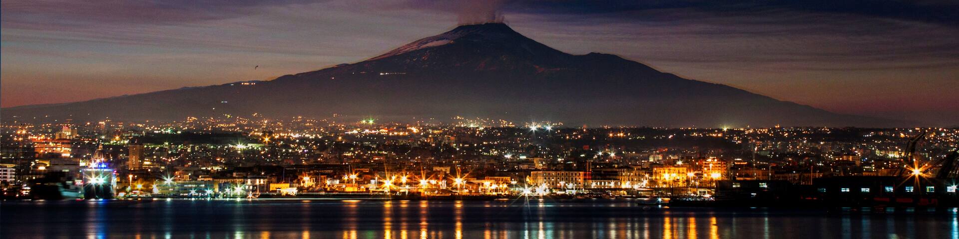 A cityscape at night with a mountain in the background.