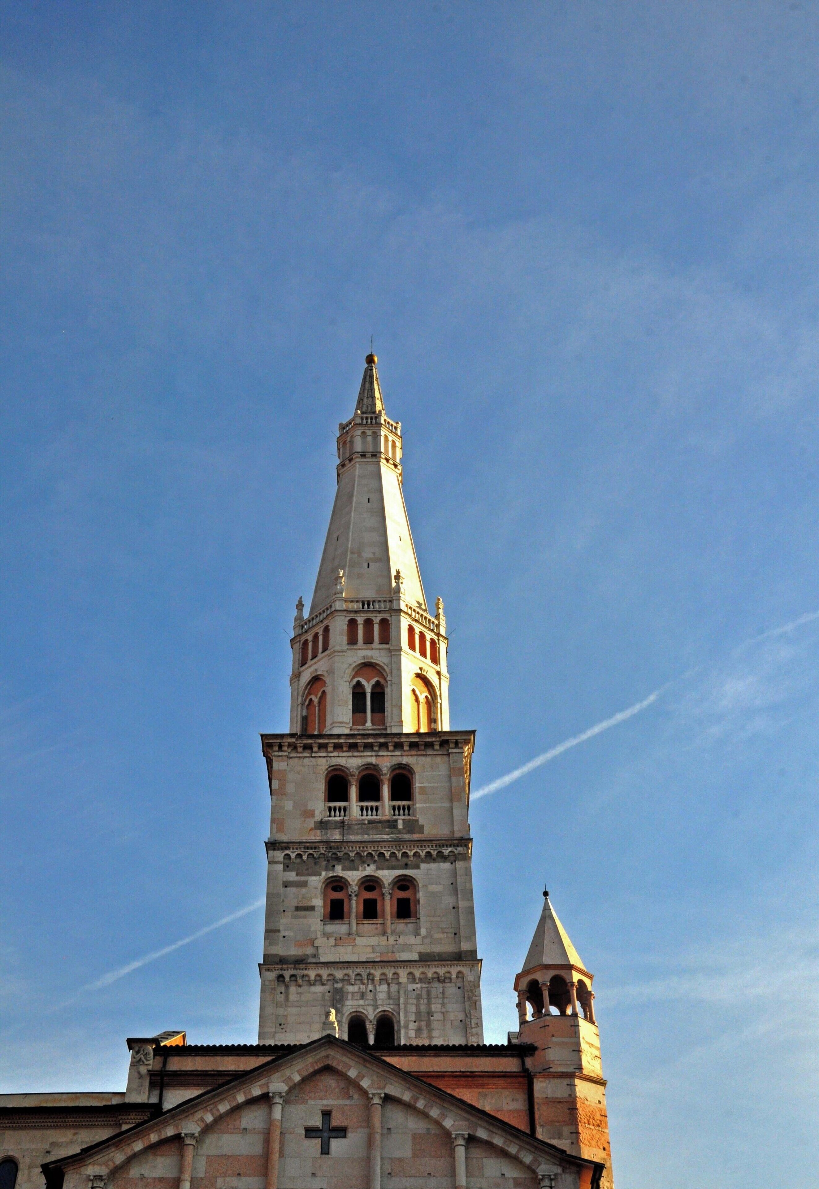 Een kerk met een hoge klokkentoren tegen een helderblauwe lucht.