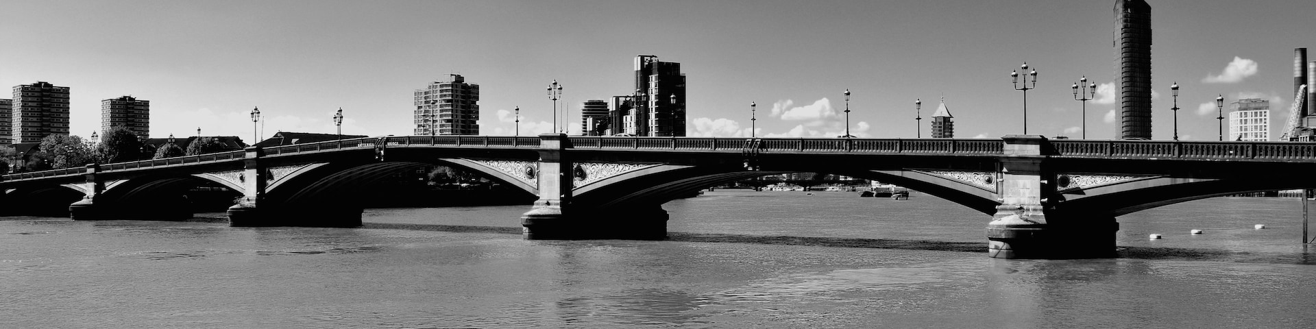 Uma ponte sobre um rio, com edifícios da cidade ao fundo.