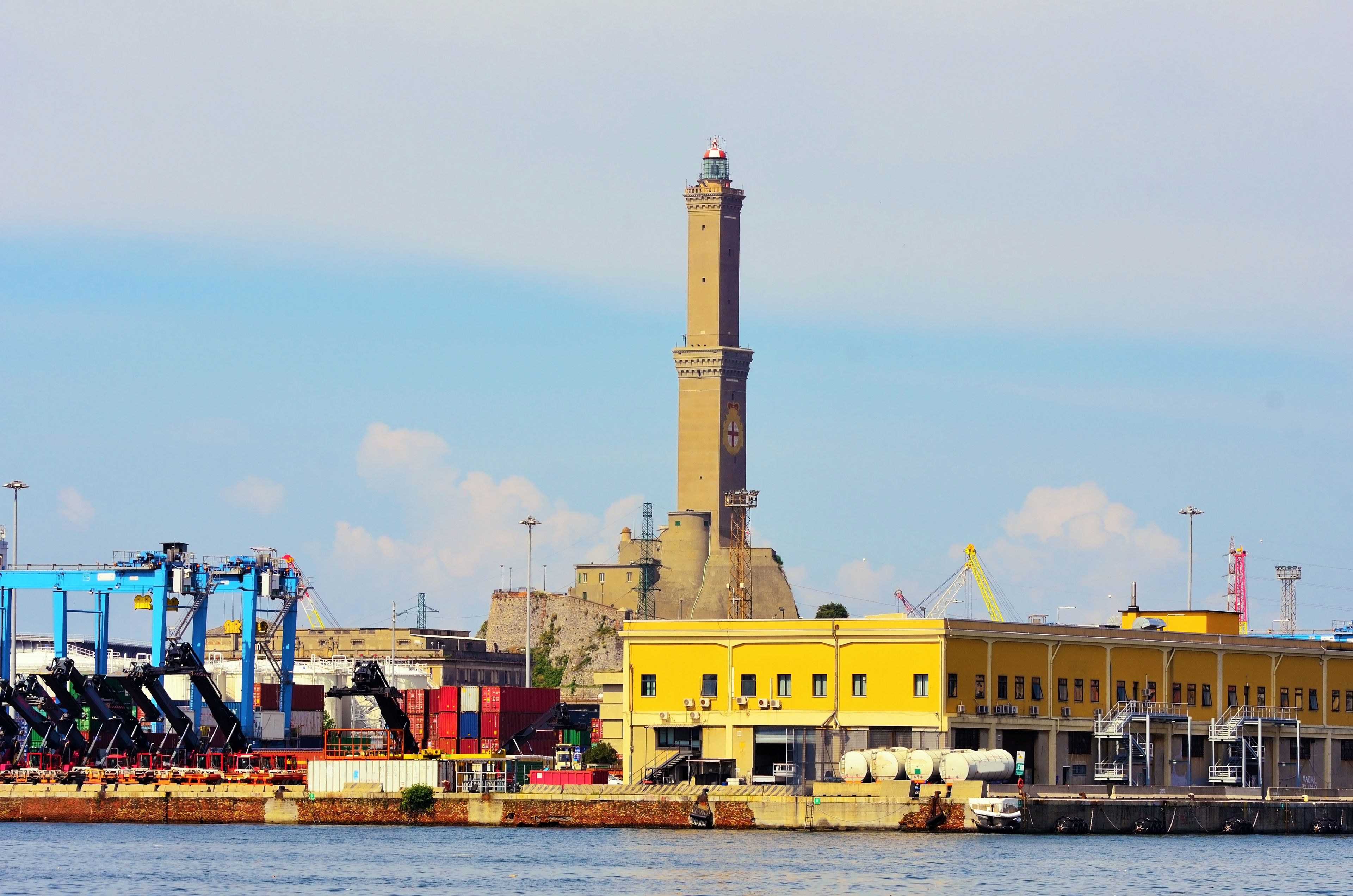 Ein Hafen mit hohem Schornstein, Containern und Industriegebäuden.