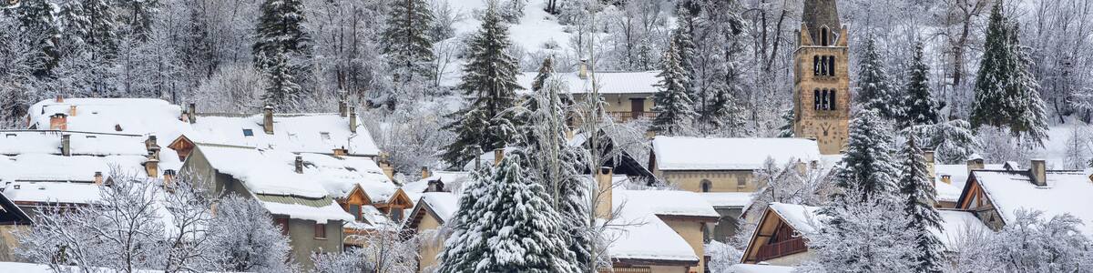 A snow-covered village with a church tower and houses.