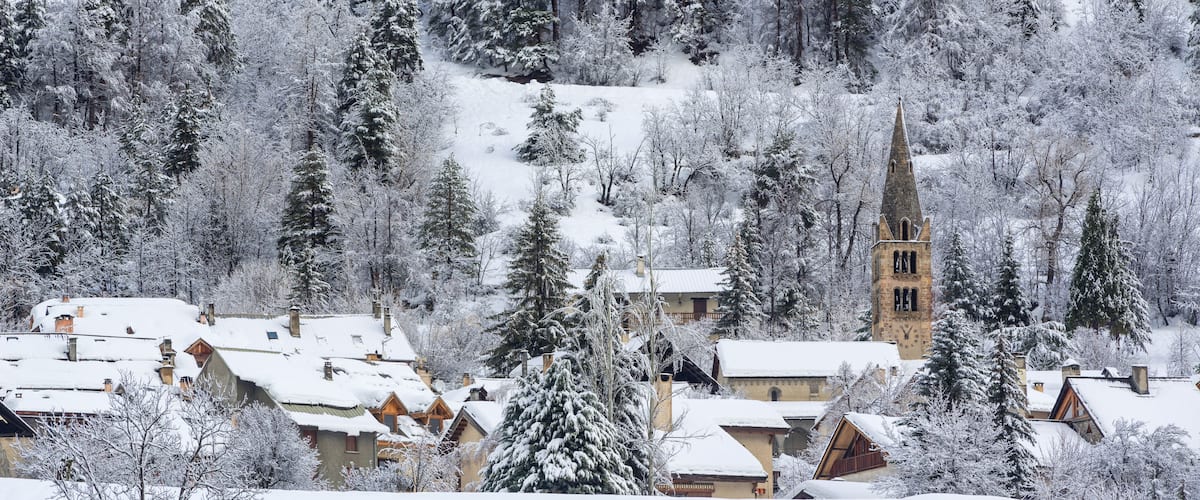 A snow-covered village with a church tower and houses.