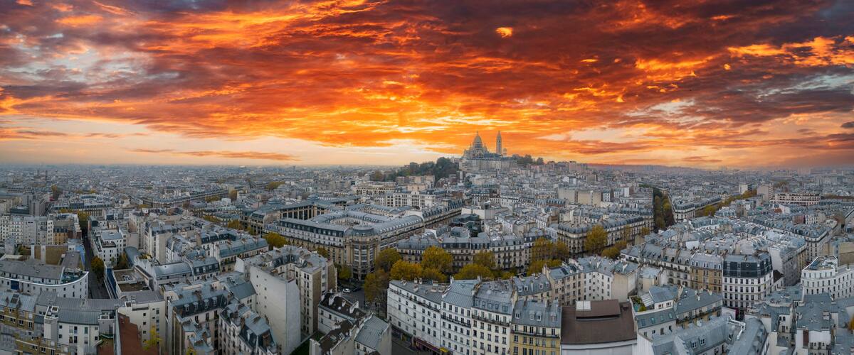 Une vue sur une ville avec une tour imposante et un ciel au coucher du soleil.