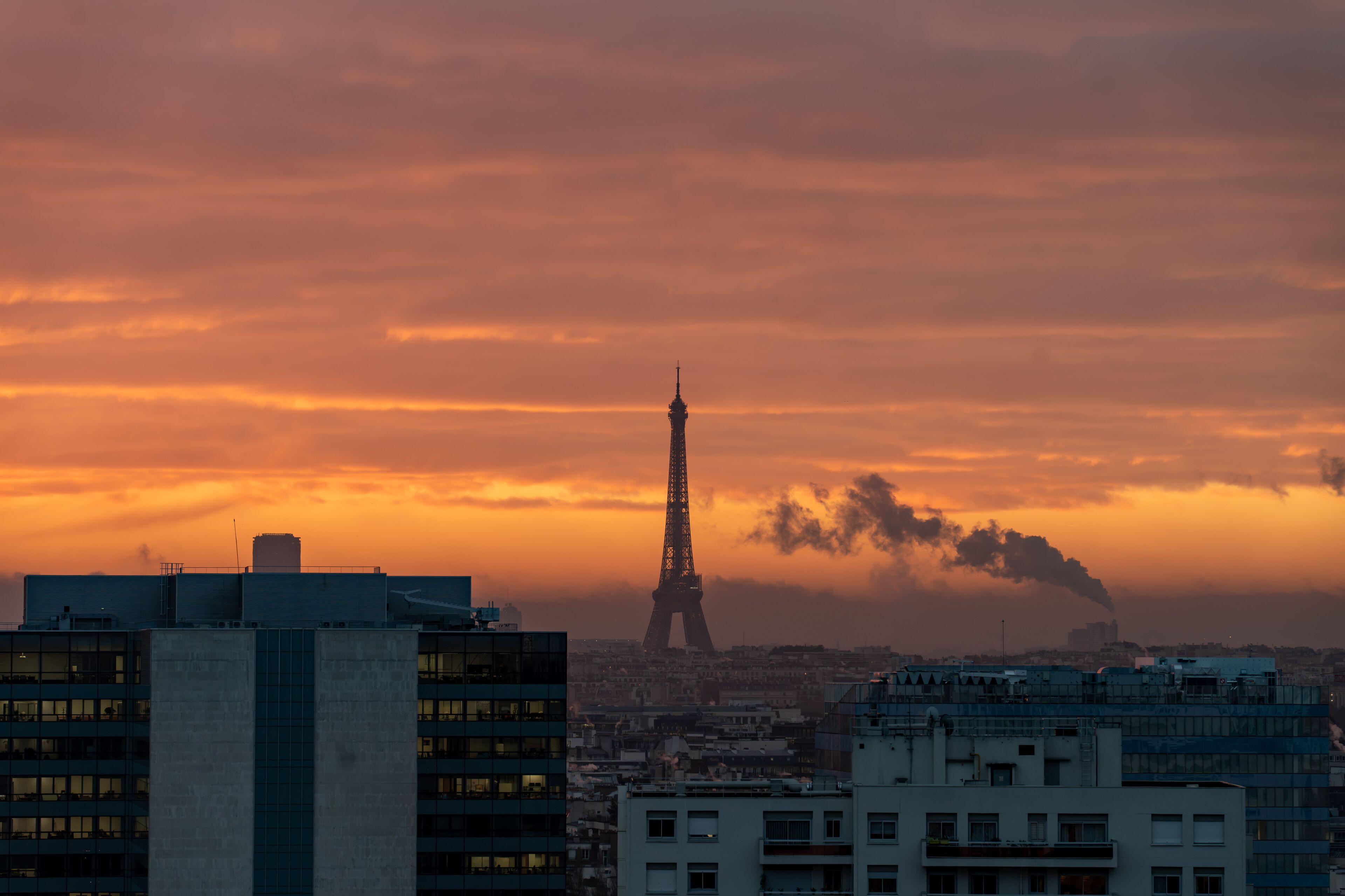 Paris city Skyline with Eiffel with city heating smoke in golden orange sky before sunrise