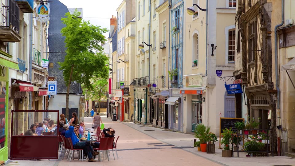 A European street with cafes, shops, and a sign for a hotel.