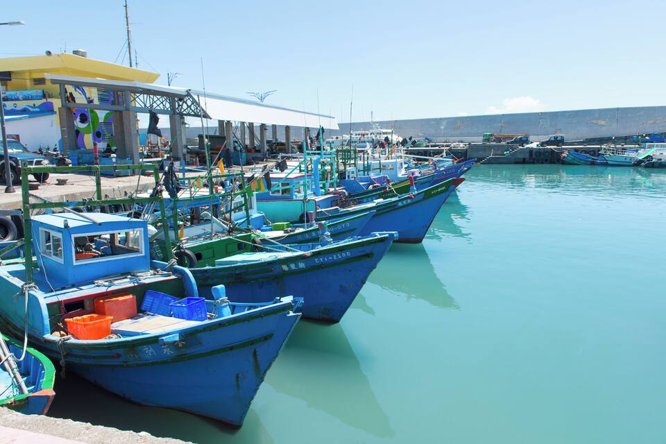 A harbor with several blue boats docked at the pier.