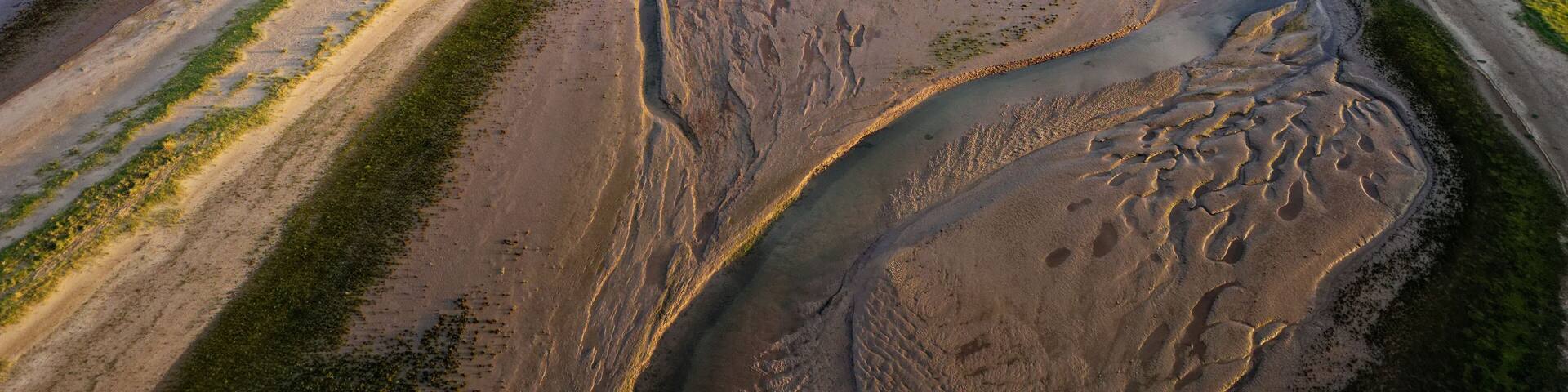 Coastal sunset scene. Aerial photograph showing tidal channels flowing through sand dunes. Lincolnshire Coast, Gibraltar Point. Summer evening sunset