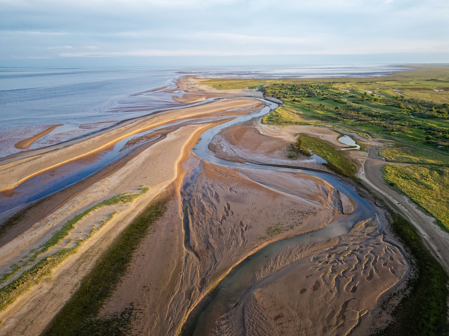 Coastal sunset scene. Aerial photograph showing tidal channels flowing through sand dunes. Lincolnshire Coast, Gibraltar Point. Summer evening sunset