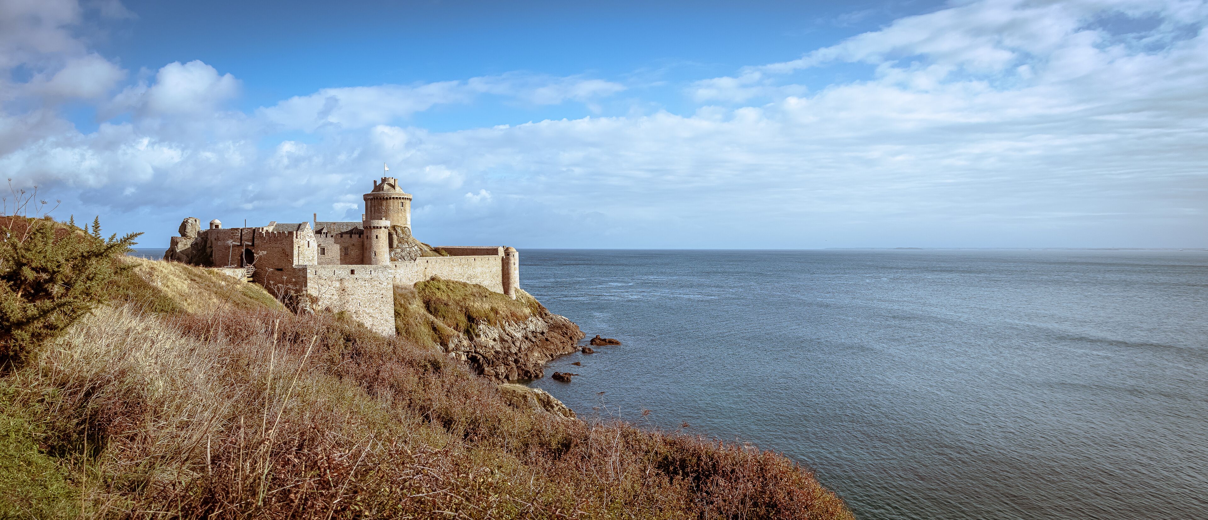A coastal castle with a tower overlooking the sea.