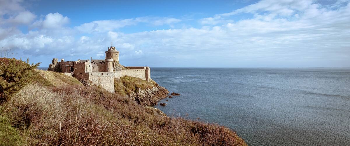 A coastal castle with a tower overlooking the sea.
