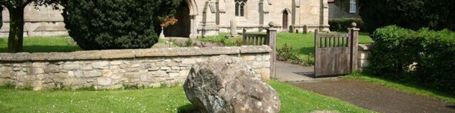 The Drake Stones. Two lumps of Spilsby sandstone by the gate to St.Ediths church known as The Drake Stones
actually a glacial erratic, but with a considerably more interesting Lincolnshire folk tale explanation. Long ago, a man ploughing a field north of the church saw his horses and plough mysteriously disappear into the ground and a dragon (drake) flew out. Next day when the villagers returned to the spot they found a stone shaped like a drakes head and thought there must be treasure beneath it. Unable to move it, the stone remained there for centuries until the 19th century when local intellectuals Dr.Oliver and Rev.Hazelwood used a traction engine to drag it to the church. It was during this relocation that the stone broke and became The Drake Stones.