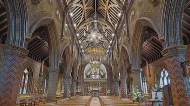Interior de igreja ornamentado, com altos tetos abobadados, madeira entalhada detalhada e um altar central.