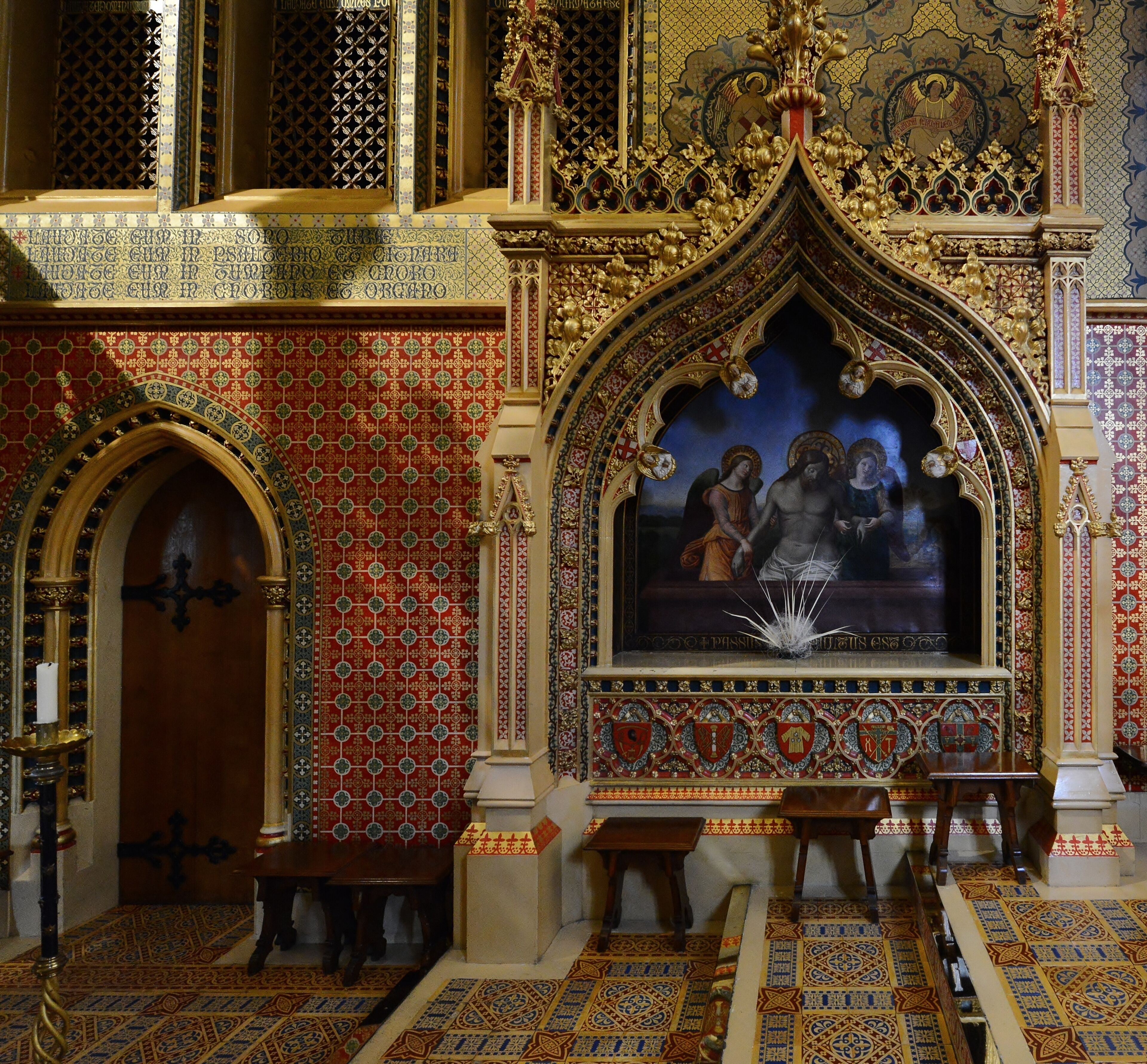 Interior de una iglesia ornamentada con un gran crucifijo, paredes con diseños y un techo detallado.