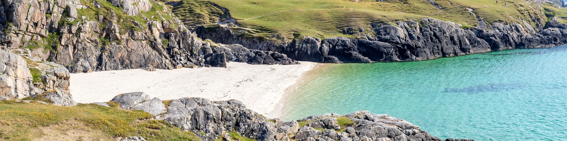 Una costa rocosa con una playa de arena y aguas turquesas cristalinas.