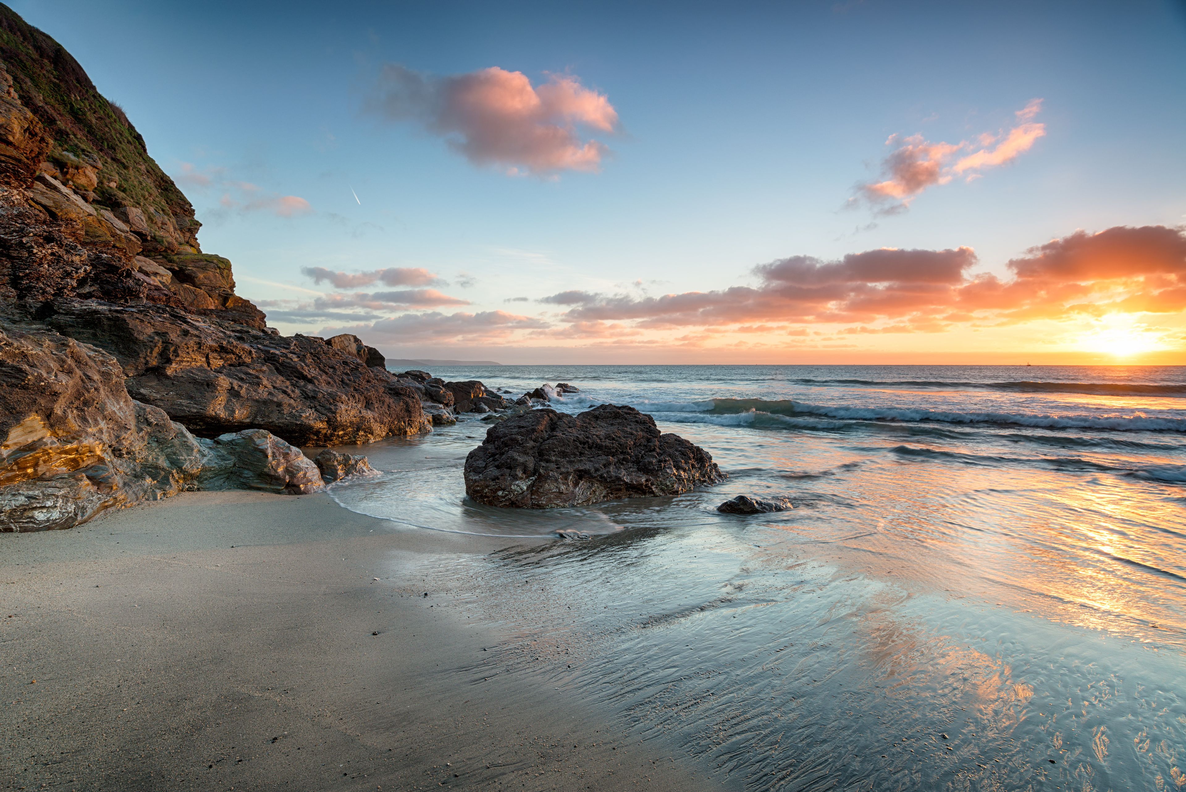 A rocky coastline with waves crashing onto the shore during sunset.