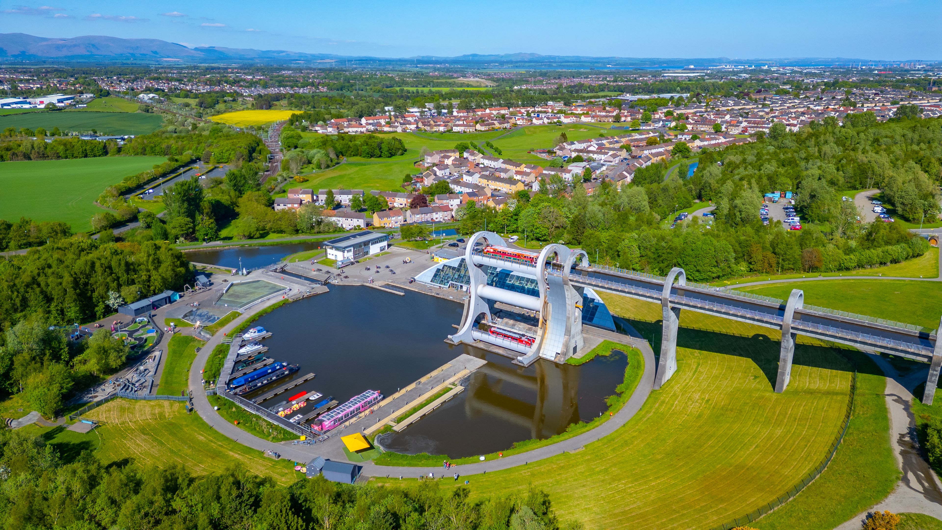 Un puente grande sobre un río, rodeado de campos verdes y zonas residenciales.