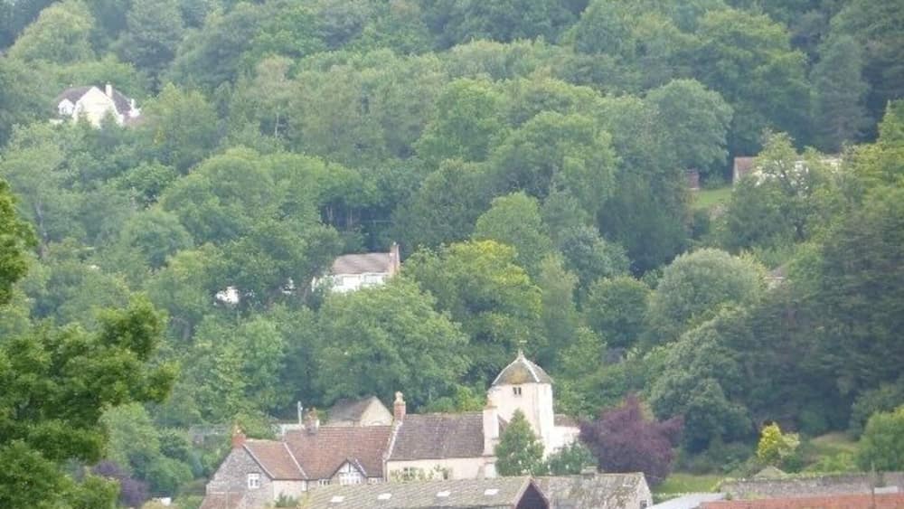 Ein Dorf eingebettet in ein Tal, mit einer markanten Kirche und mehreren Häusern, umgeben von dichtem Grün.