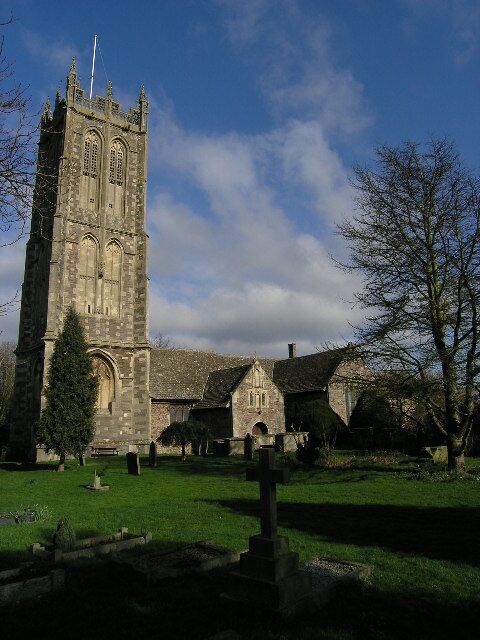 A historic church with a tall tower, a cemetery, and a clear sky.