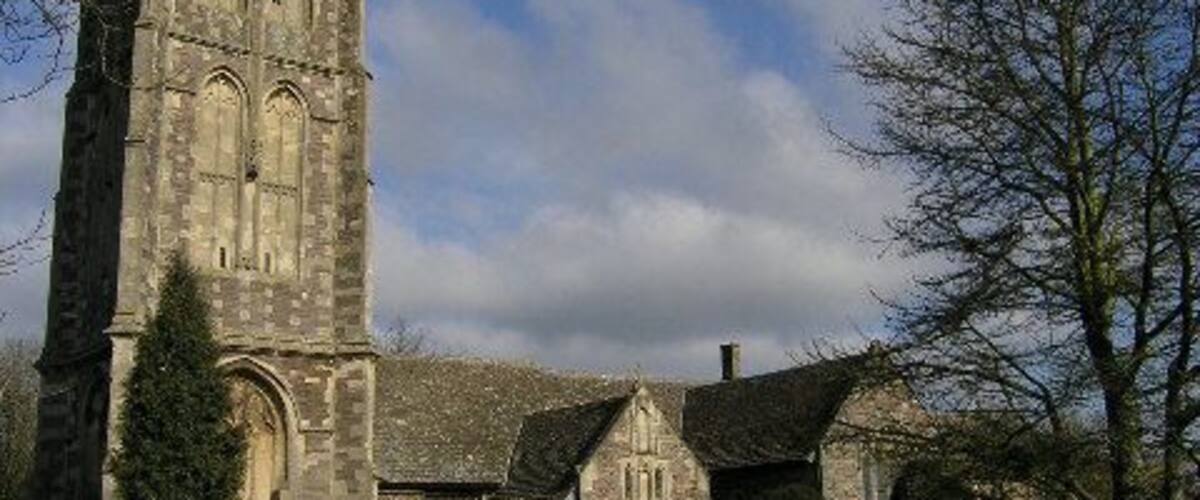 A historic church with a tall tower, a cemetery, and a clear sky.