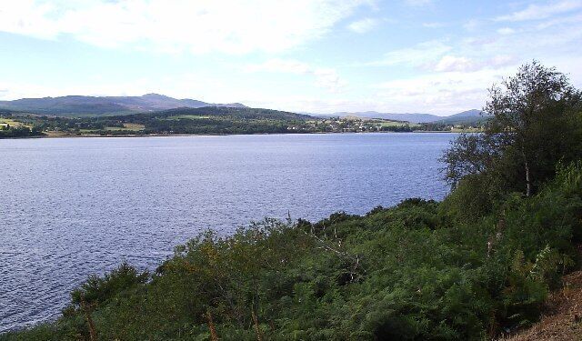 A lake surrounded by hills and greenery.