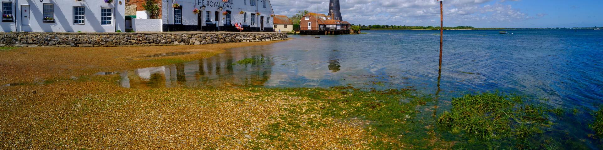 A waterfront scene with buildings, a lighthouse, and a clear sky.