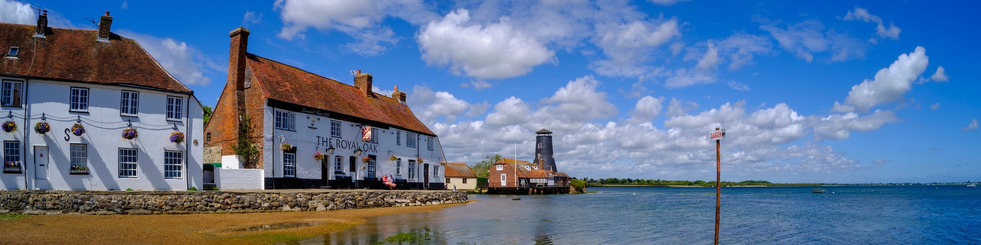 Eine Uferlandschaft mit Gebäuden, einem Leuchtturm und einem klaren Himmel.