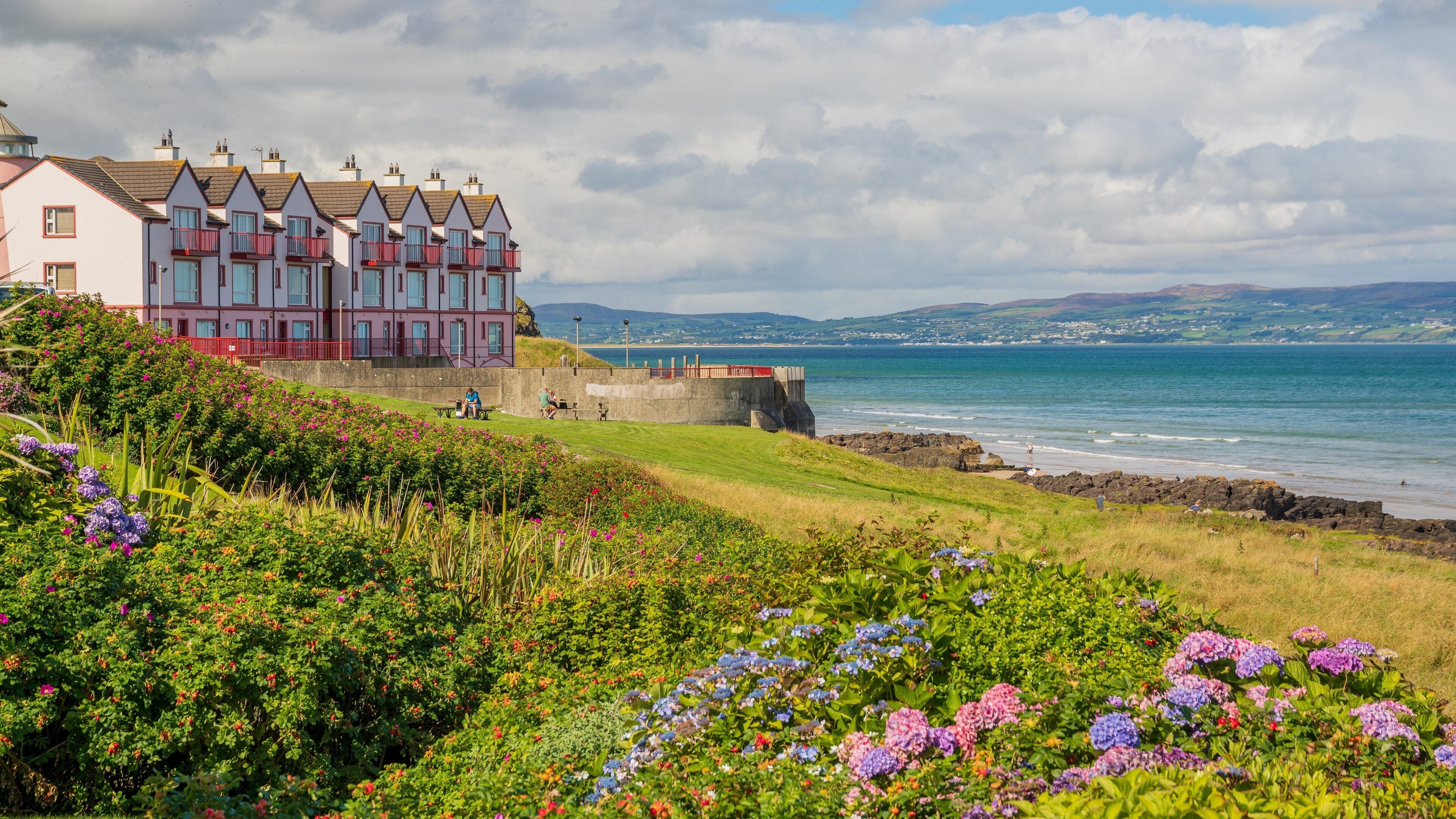 A coastal town with colorful houses, a beach, and a rocky shoreline.
