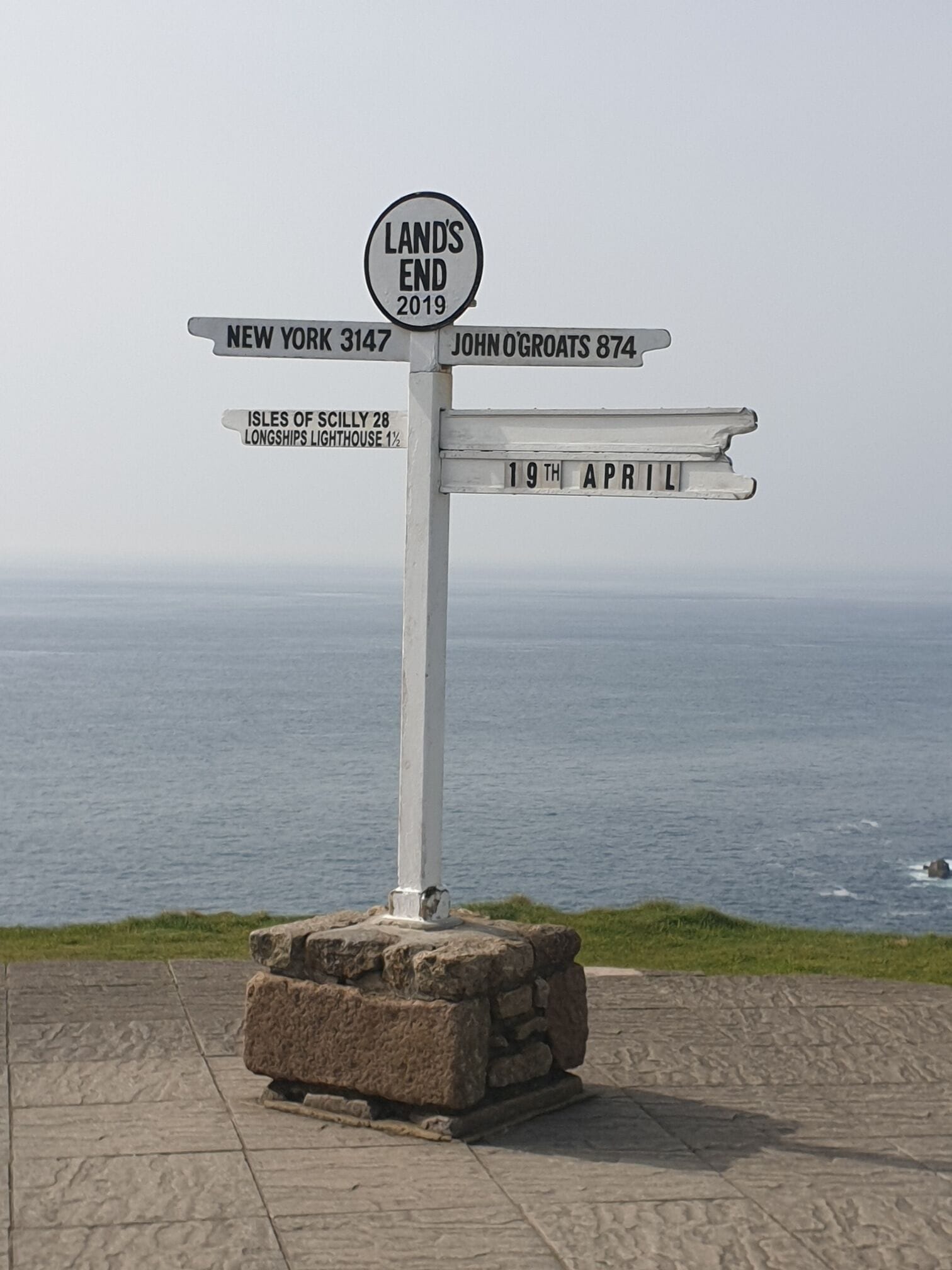 A directional signpost with multiple destinations and a date.