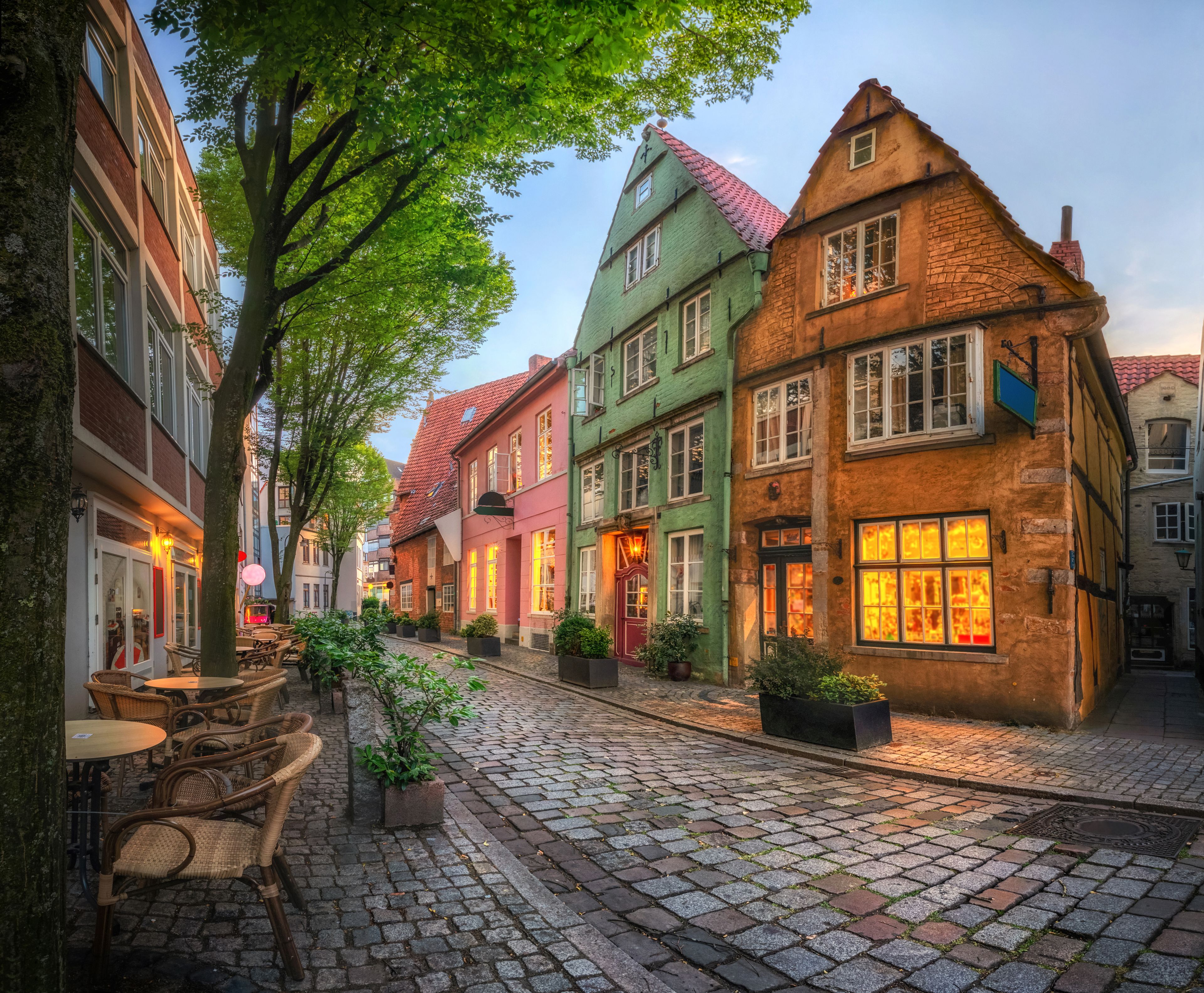Une rue pavée bordée de bâtiments colorés et d’arbres.