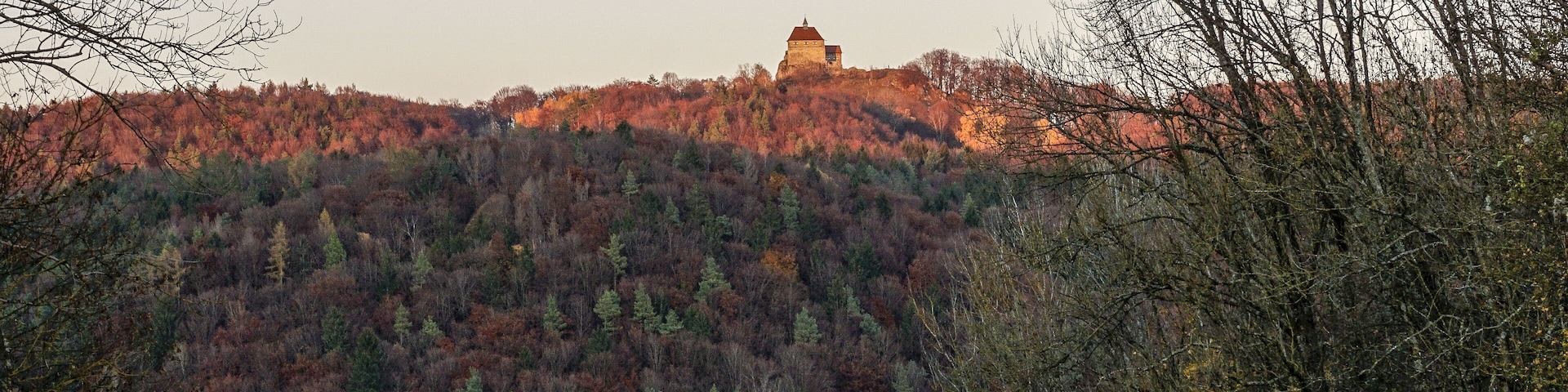 Castle Burg Hohenstein on the hill with colorful forest in the autumn evening light