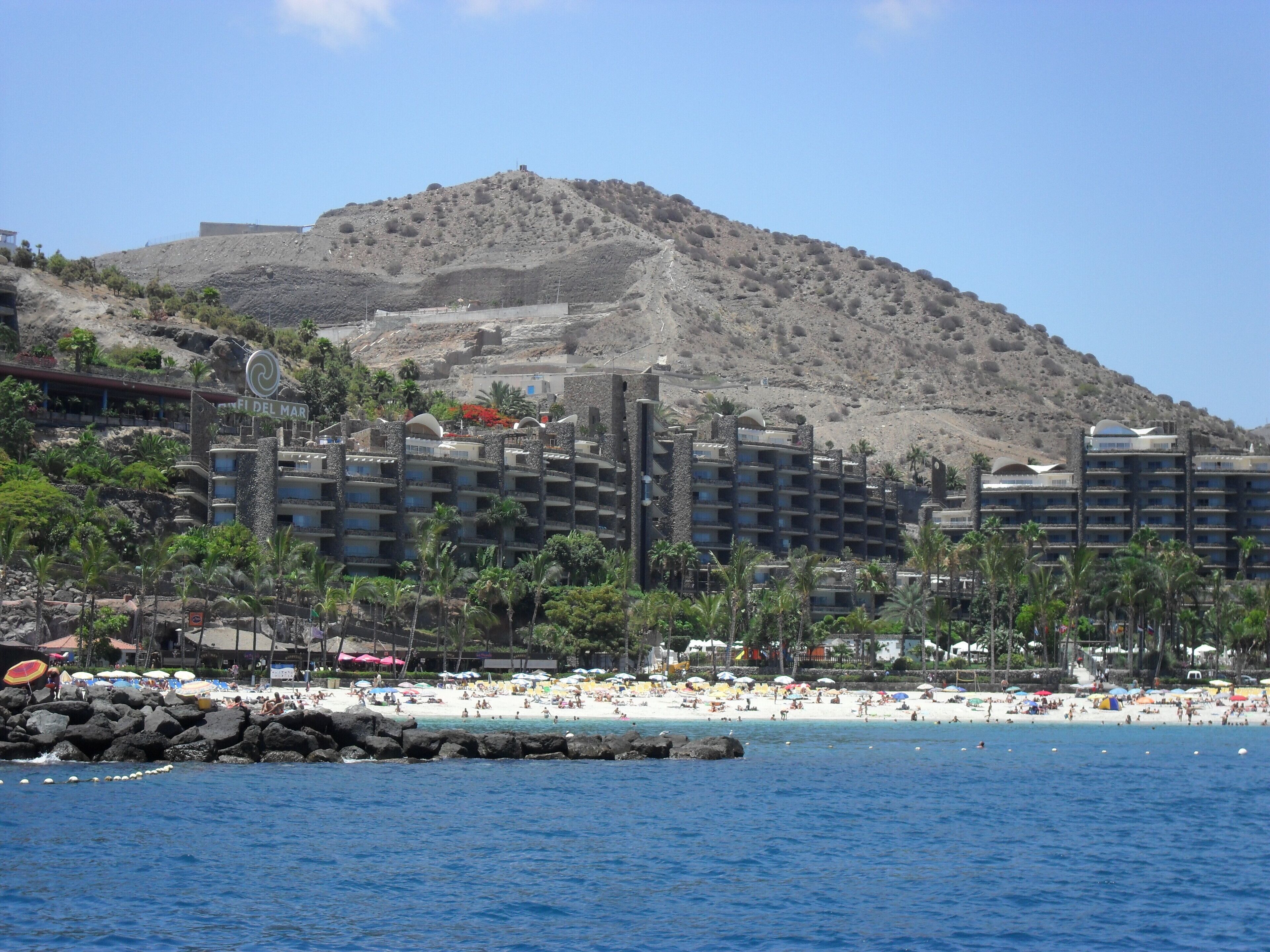 A beach with a rocky hill in the background.