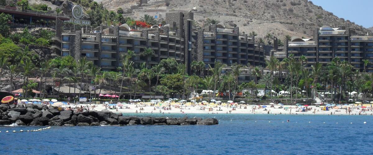 A beach with a rocky hill in the background.