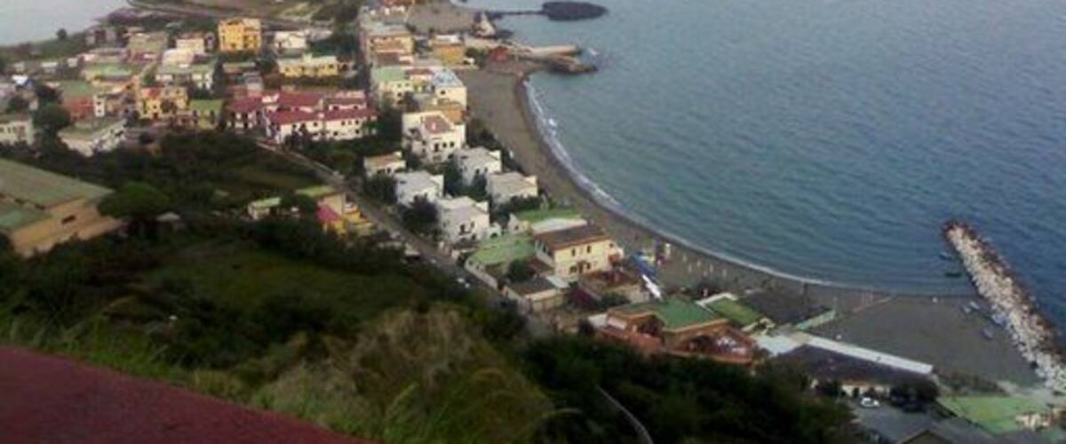 A coastal town with a long beach, a prominent hill, and a pier extending into the sea.