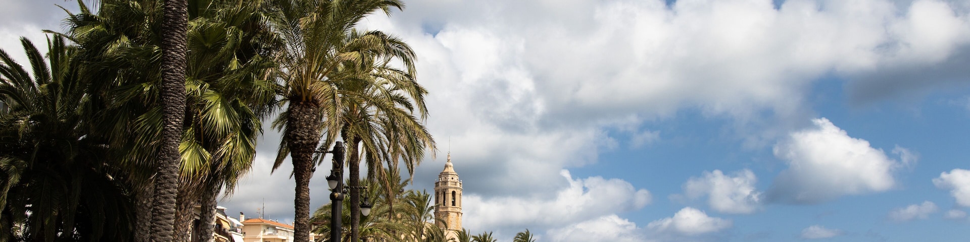 Empty promenade Passeig de la Ribera with the views of church Sant Bartomeu y Santa Tecla, Sitges, Catalonia, Spain
