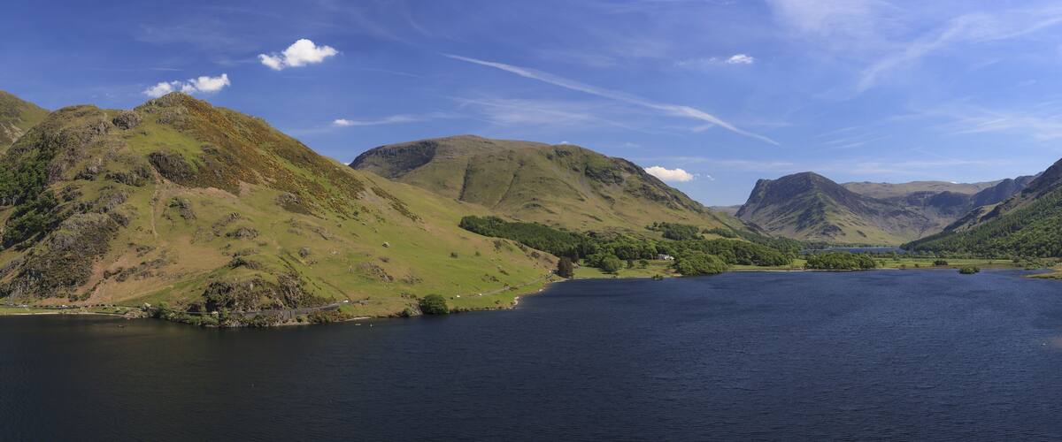 A lake surrounded by green hills and mountains.