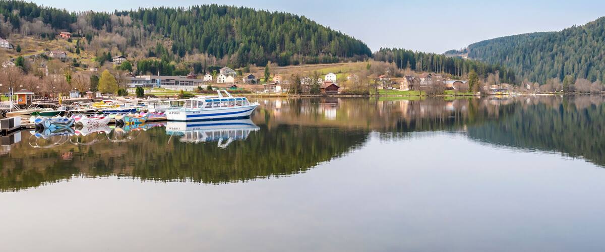 Bateaux pour visiter et découvrir le lac de Gérardmer dans les Vosges. Paysage de montagne et de conifères.