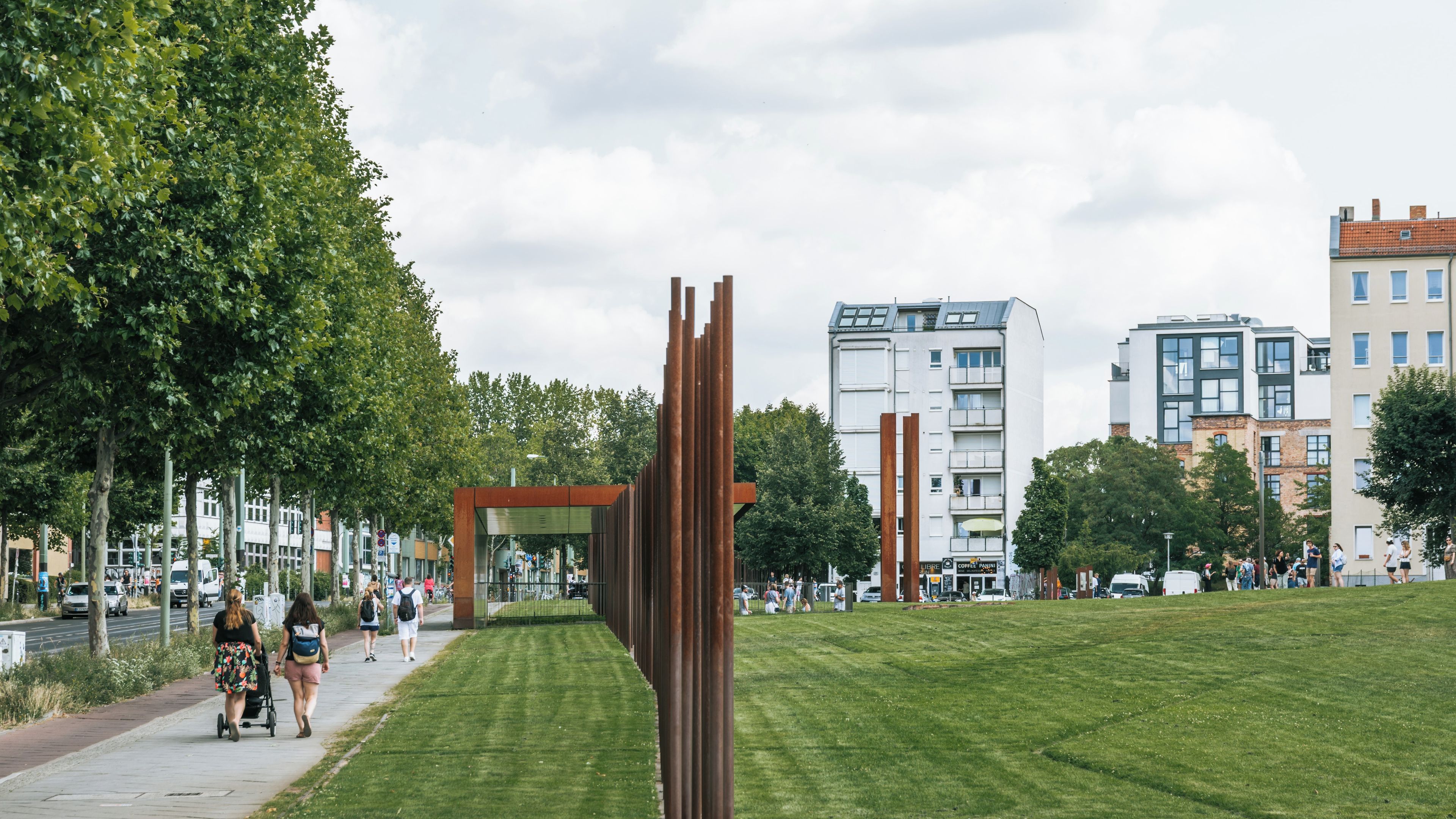 Un parc agrémenté d’une sculpture moderne, d’une pelouse et, en arrière-plan, de bâtiments urbains.