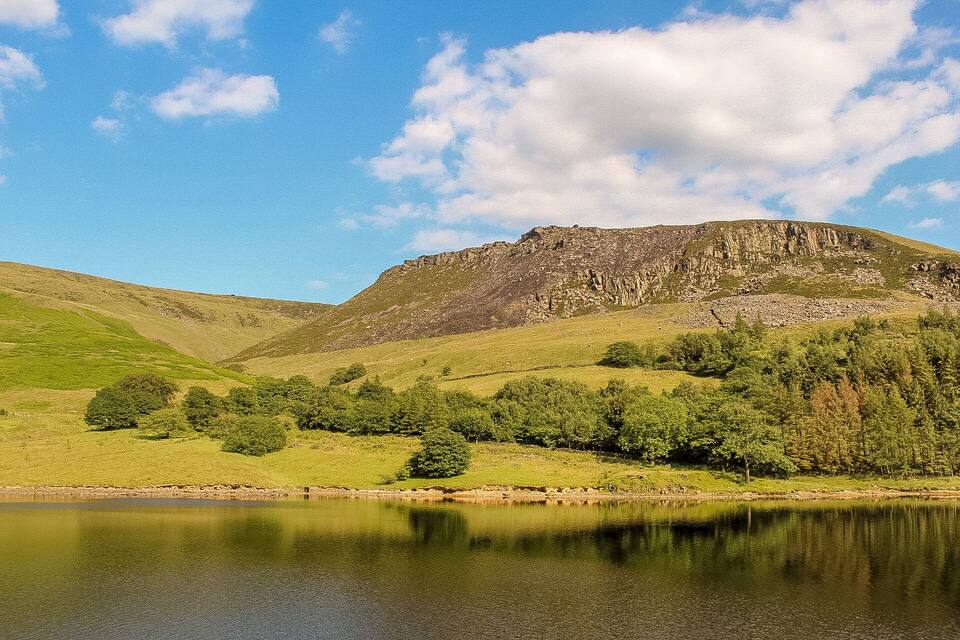 A lake surrounded by green hills and a rocky mountain.