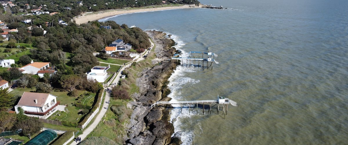 Un pueblo costero con playa, casas y un litoral rocoso.