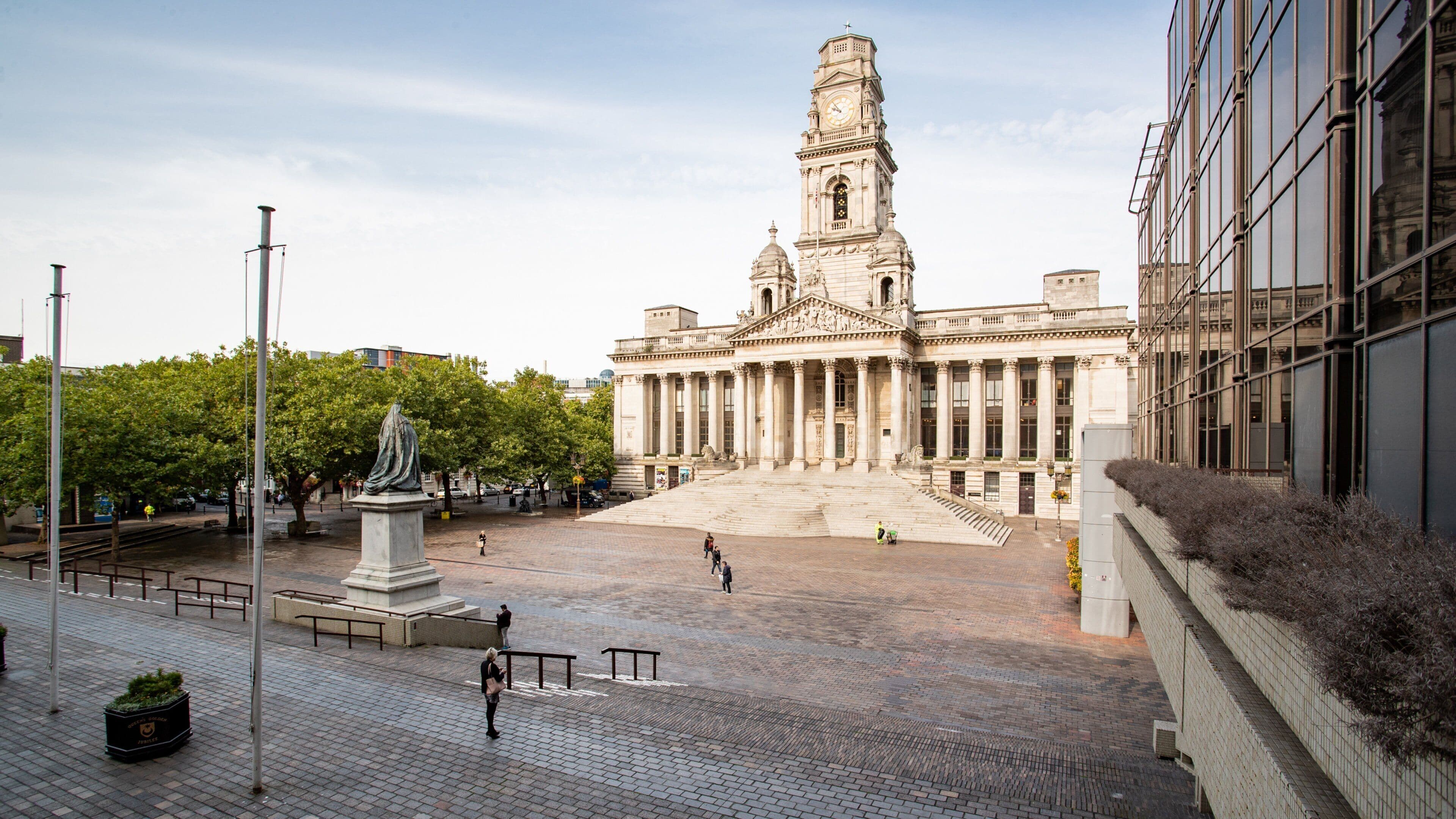 A large public square with a prominent building featuring a tall clock tower.